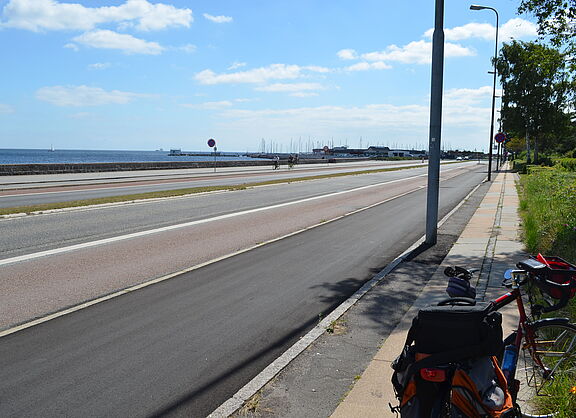 Uferpromenade nördlich von Kopenhagen. Hier ist Platz für alle: Vom Rand zur Mitte gibt es gleichberechtigt Fußweg, Radweg, einen Trennstreifen, Kfz-Fahrbahn und einen schmalen Grünstreifen.